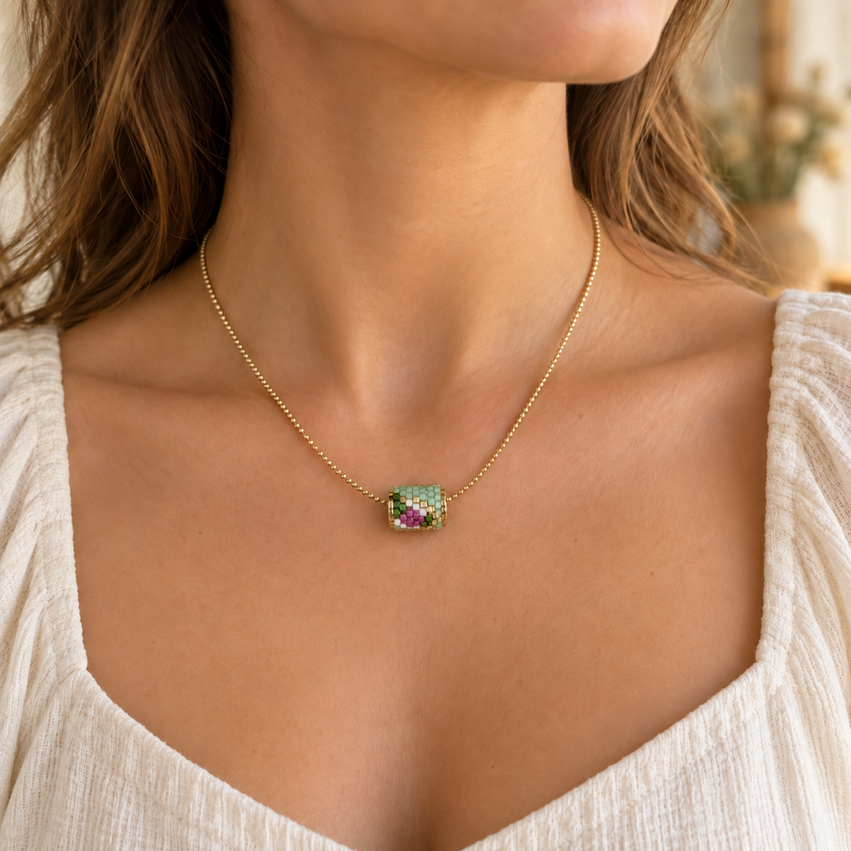 Gold-toned chain necklace with mint green, white and pink cylindrical beadwork — styled view