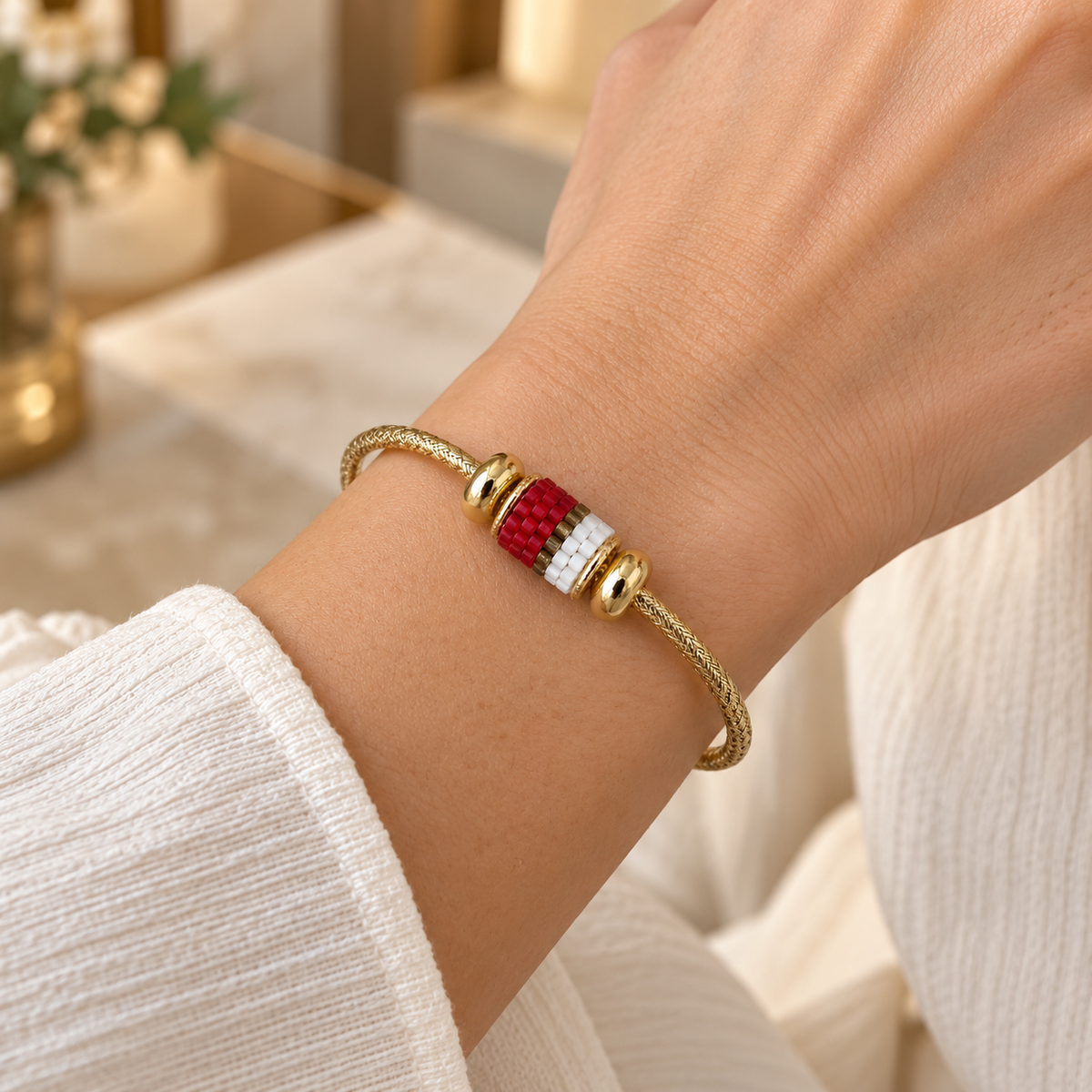 Gold-toned open cuff bracelet with scarlet, white and gold-toned striped beadwork — styled view