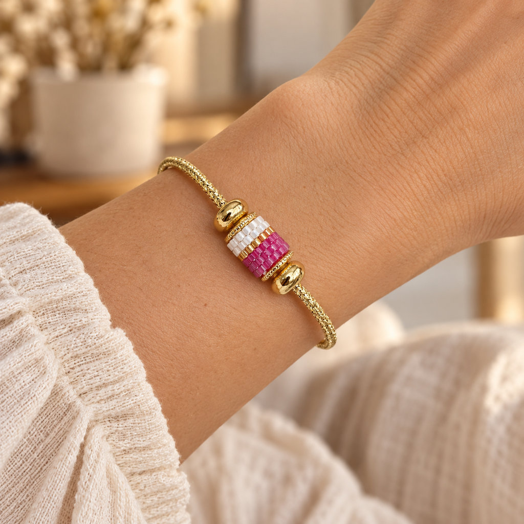 Gold-toned open cuff bracelet with pink, white and gold-toned cylindrical beadwork — styled view