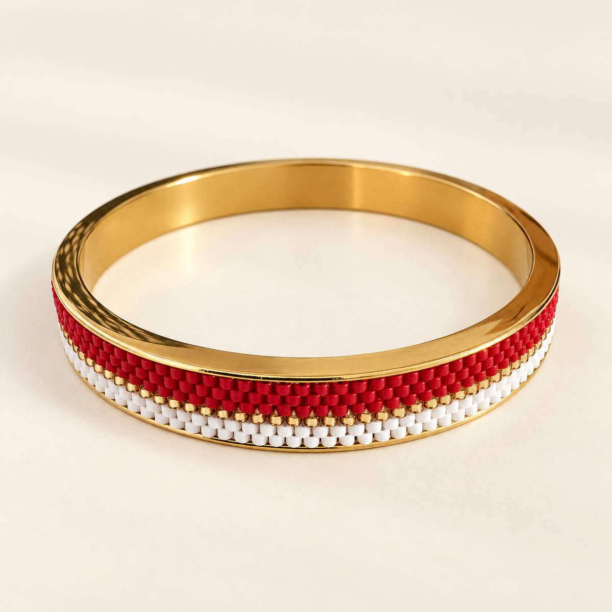 Gold-toned bangle with scarlet red and white beadwork and a fine gold-toned line