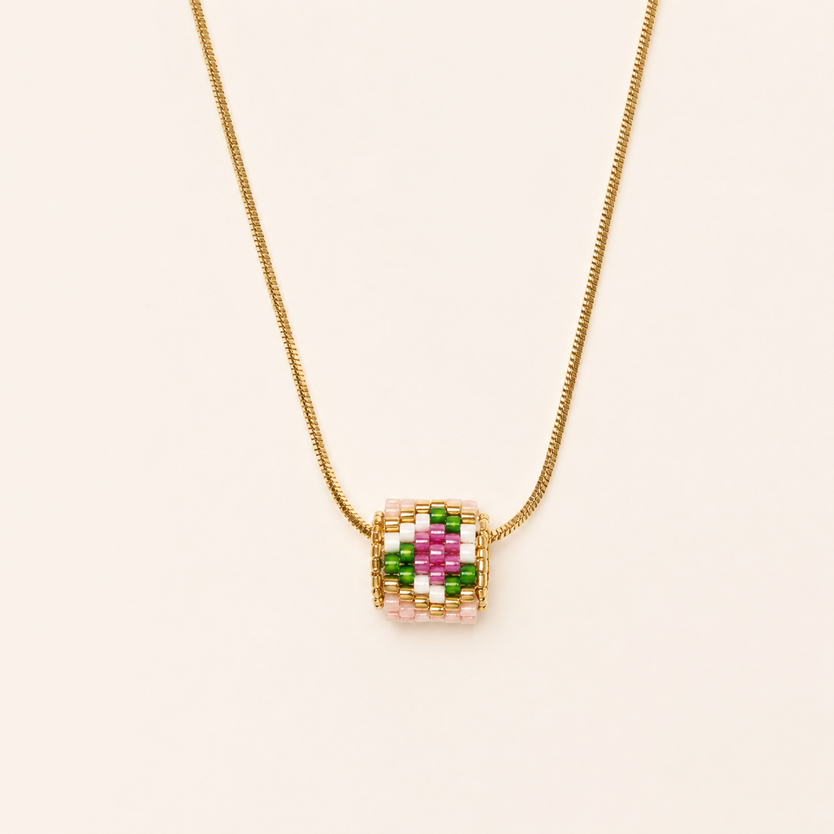 Gold-toned necklace with a pink, green, white and magenta geometric beaded pendant