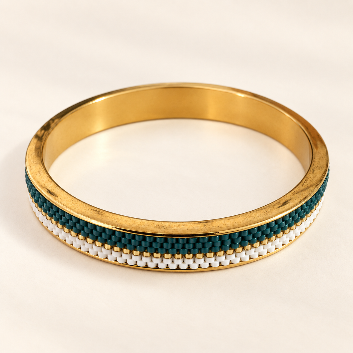 Gold-toned bangle with deep teal, white and gold-toned beadwork